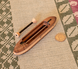 Brocade10 top view 5 5/8" L x 1" W x 3/4" H.  0.9 oz. black walnut featherwood top/bottom and tiger maple center. Includes 1 carbonfiber bobbin. Ebony fittings over rod slots; stainless steel rod and yarn hole fitting.