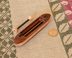 Brocade9 top view 5 3/8" L x 1" W x 13/16" H.  0.9 oz. black walnut featherwood top/bottom and figured oak center. Includes 1 carbonfiber bobbin. Ebony fittings over rod slots; stainless steel rod and yarn hole fitting.